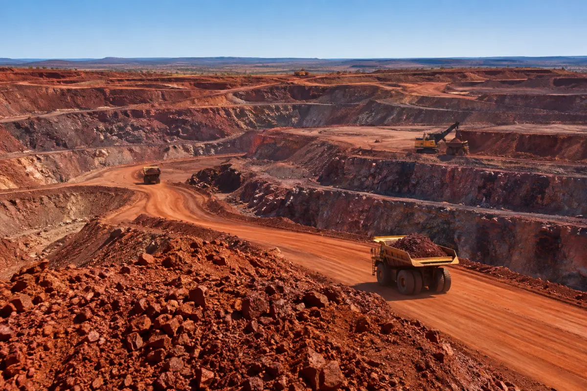 Haul trucks carrying iron ore out of an open-pit mine